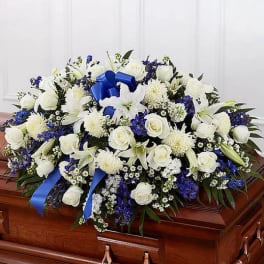 White and blue funeral spray on a casket with ribbon