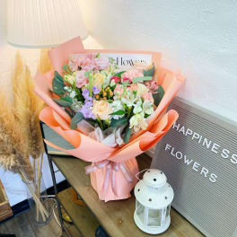 Pastel bouquet of mixed flowers wrapped in peach paper
