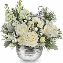 White roses and blossoms in a silver vase with pine accents and ornaments
