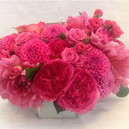 Pink bouquet of roses and dahlias in a clear square vase
