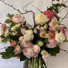 Pink and white flowers arranged in a clear glass vase with branching stems