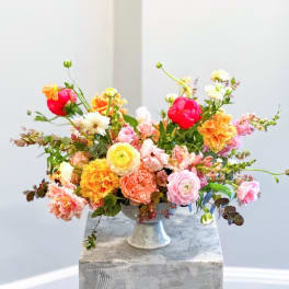 Colorful mixed flower arrangement in a white pedestal vase