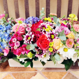Colorful mixed flower arrangement in a white rectangular container