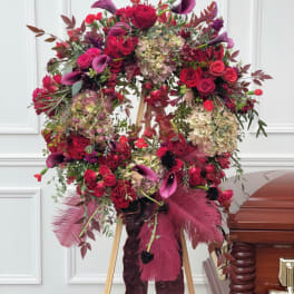 Large red floral wreath on an easel beside a casket