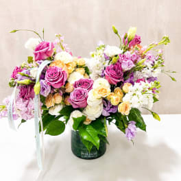 Mixed pink, white, and peach roses in a dark glass vase