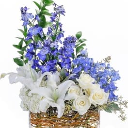 White lilies and roses with blue flowers in a glass vase