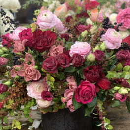 Mixed pink and red flower arrangement in a black container