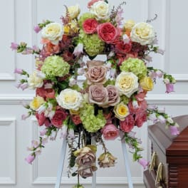 Large floral wreath on an easel beside a casket