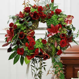 Large red floral wreath with roses and lilies on a stand