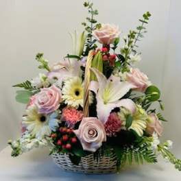 Basket arrangement of pink roses, lilies, and daisies