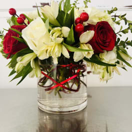 Red and white flower arrangement in a clear glass vase with a red ribbon