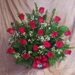 Red roses arranged in a basket with baby's breath and a red ribbon