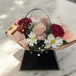 Bouquet of pink and red roses with white daisies in pink wrap