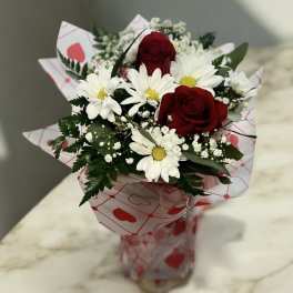 Bouquet of red roses and white daisies in heart-patterned wrap