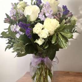 Bouquet of white roses and purple flowers in a glass vase