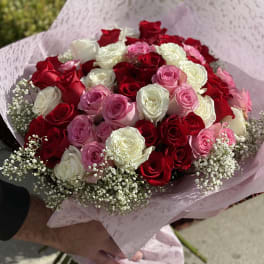 Bouquet of red, pink, and white roses wrapped in pink paper