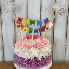 Birthday cake made of pink, white, and purple flowers with a banner topper