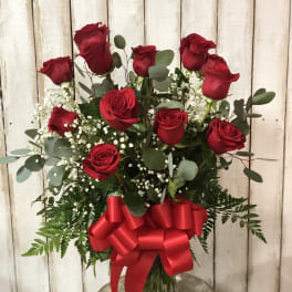 Red roses in a glass vase with a large red bow