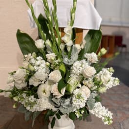 White floral arrangement in a white pedestal vase with tall green stems
