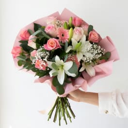 Pink and white mixed bouquet with roses, lilies, and gerbera daisies wrapped in pink paper