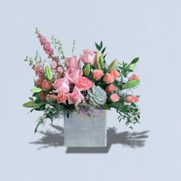 Pink roses and lilies arranged in a square gray box