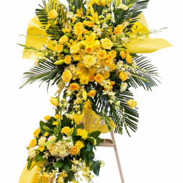 Yellow floral standing spray with roses and lilies on a stand