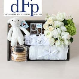 Gift basket with white flowers, a plush bunny, cookies, and folded baby clothes