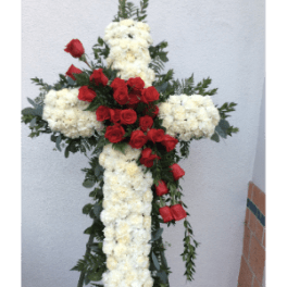 Floral cross made of white flowers with red roses and greenery