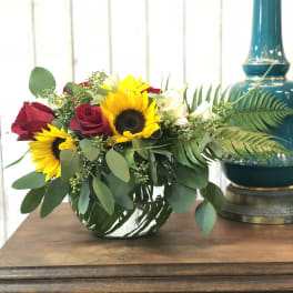 Bouquet of red roses and sunflowers in a low glass vase