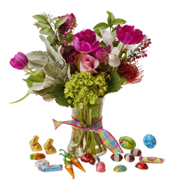Bouquet of pink tulips and roses in a glass vase with assorted chocolates