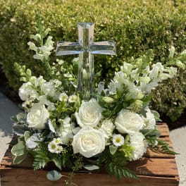 White floral arrangement with a clear cross centerpiece in a wooden box