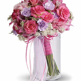 Pink and lavender rose bouquet in a clear glass vase with ribbon