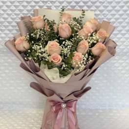 Bouquet of pale pink roses with baby's breath in mauve wrapping