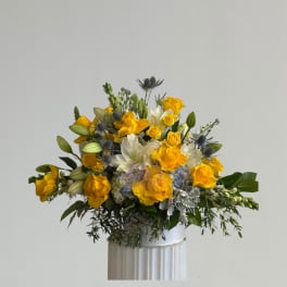 Yellow and white floral arrangement in a white vase