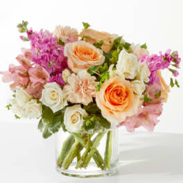 Bouquet of peach and white roses with pink flowers in a clear glass vase