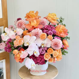 Bouquet of orange, pink, and white flowers in a white vase