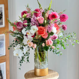 Tall mixed bouquet of pink, white, and coral flowers in a glass vase