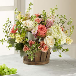 Mixed pink and white flowers in a wooden basket on a table