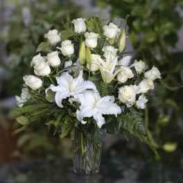 White roses and lilies arranged in a clear glass vase