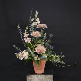 Tall pastel floral arrangement in a terracotta vase