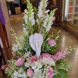 Pink and white floral arrangement with an angel figurine centerpiece