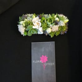 Compact floral arrangement with white blooms and green succulents