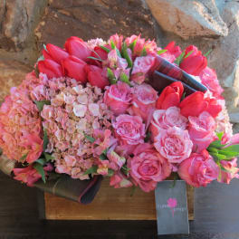 Pink and red bouquet with roses, tulips, and hydrangeas in a box