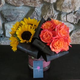 Sunflowers and orange roses in a black-wrapped vase arrangement