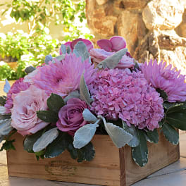 Pink floral arrangement in a wooden box with roses and hydrangea