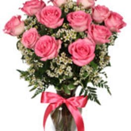 Pink roses arranged in a glass vase with a pink ribbon