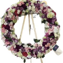 Large circular floral wreath on a stand with pink, purple, and white roses