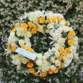 Large floral wreath of white and yellow blooms on a flower-covered backdrop