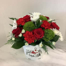 Red and white flower arrangement in a white holiday tin