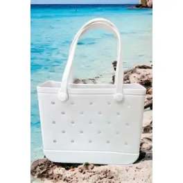 White perforated tote bag with a curved handle on a beach